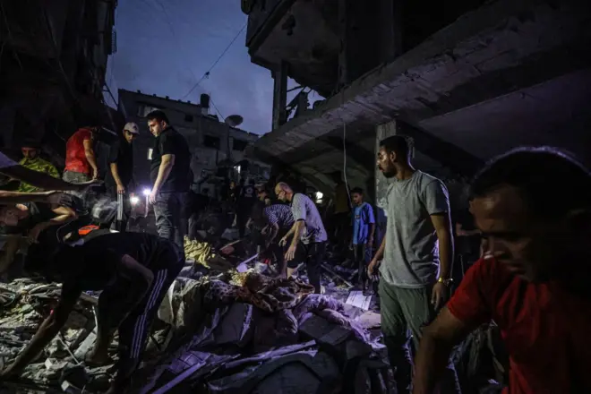 Des équipes de défense civile et des civils mènent une opération de recherche et de sauvetage sous les décombres des bâtiments démolis après une attaque israélienne sur une résidence familiale à Khan Yunis, Gaza, le 13 novembre 2023.