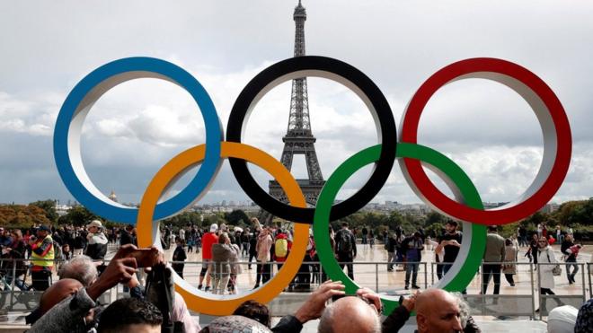People take photos of Olympic rings in front of the Eiffel Tower in Paris. File photo