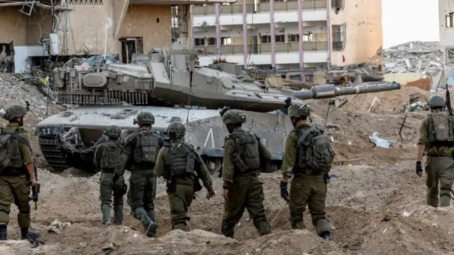 Israeli soldiers walk through rubble in the northern Gaza Strip