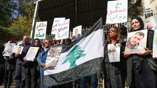 أقارب ضحايا انفجار مرفأ بيروت يحملون صورهم