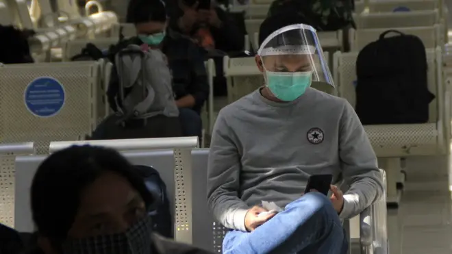 Seorang penumpang pesawat menggunakan pelindung wajah duduk di ruang tunggu keberangkatan bandara El Tari Kupang, NTT, Senin (08/06). Pemprov NTTkembali membuka jalur penerbangan dari dan ke Kupang sebagai persiapan menyambut 'era normal baru' di daerah itu.