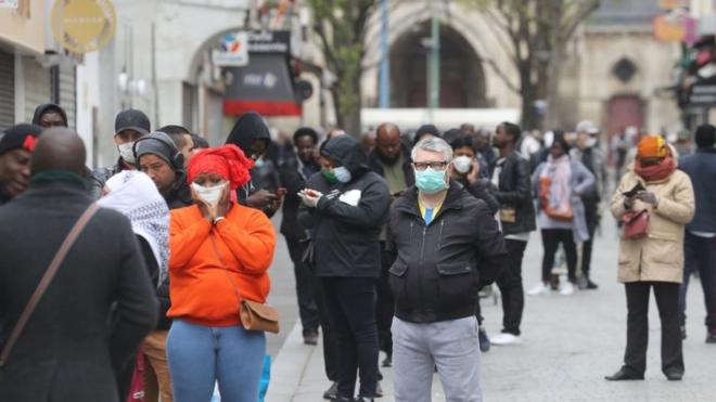 Transeúntes con mascarillas frente a una oficina de correos en Saint Denis, Francia.