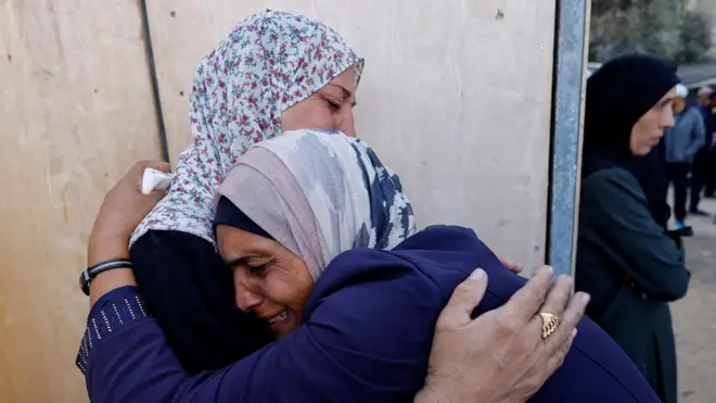 Women hug each other during the funeral of Palestinians killed in Israeli strikes, at al-Awda Hospital, in central Gaza (20 October 2025)