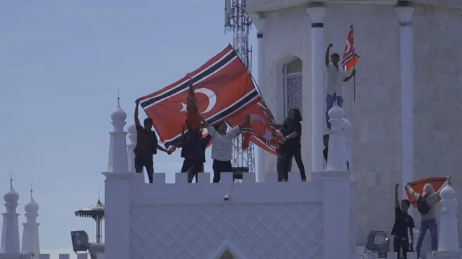 Sejumlah orang membentang bendera bulan bintang di Masjid Raya Baiturrahman, Banda Aceh, dalam Peringatan 21 tahun Hari Damai Aceh, pada Sabtu (15/08).