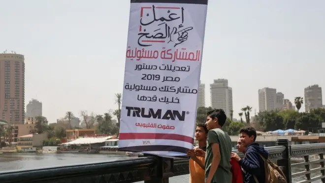 أطفال يتفقدون لافتة دعائية للمشاركة في الاستفتاء على التعديلات الدستورية