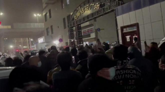 حشد من عشرات الأشخاص يسيرون في شوارع أورومتشي ليلا