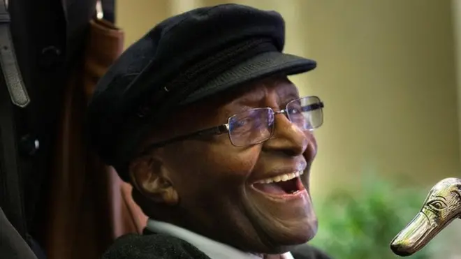 Desmond Tutu smiles in a wheelchair
