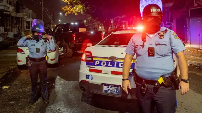Police officers guard a pick-up truck loaded with looted merchandise following protests over the police shooting death of Walter Wallace in Philadelphia, Pennsylvania