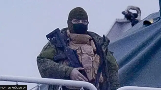 ఓడపై రైఫిల్‌తో నిల్చున్న వ్యక్తి