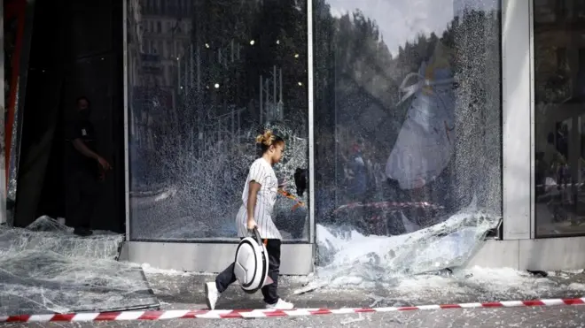 2023년 6월 30일, 한 여성이 프랑스 파리에서 일어난 폭동으로 부서진 나이키 매장 앞 유리창을 지나고 있다. 앞서 경찰이 6월 27일 낭테르의 한 교통 정류장에서 17세 나엘을 사살한 후 프랑스 전역에서 폭동이 발생했다.