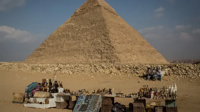 رجل يبيع التذكارات أمام أحد أهرامات الجيزة