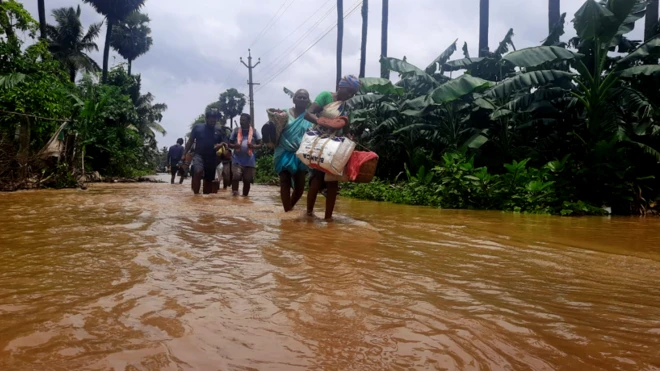 వరద నీటిలో సురక్షిత ప్రాంతాలకు తరలి వెళుతున్న ప్రజలు