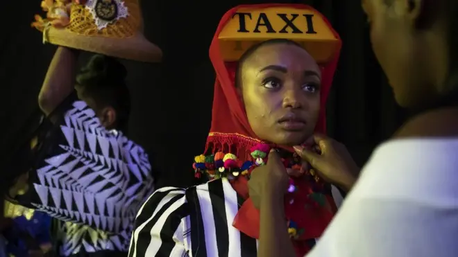 Gabdhaha dharka xayeysiiya oo la diyaarinayo ka hor inta aysan soo hormarin dadka daawanaya, xarunta Hub of Africa, oo lagu qabtay todobaadka bandhigga dharka ee Afrika 03 Oktoobar.