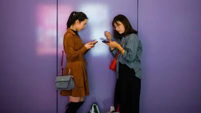 Dos mujeres usando sus celulares en China