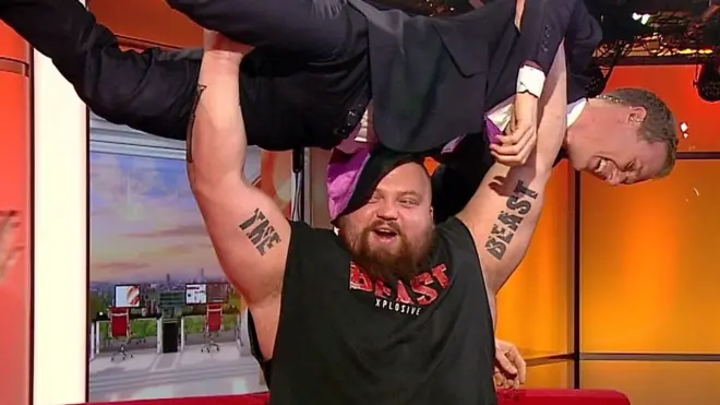 أقوى رجل في العالم، إدي هول، يستعرض قوته من خلال رفع مذيع في برنامج "بي بي سي بيركفاست"، دان ووكر، على الهواء مباشرة.