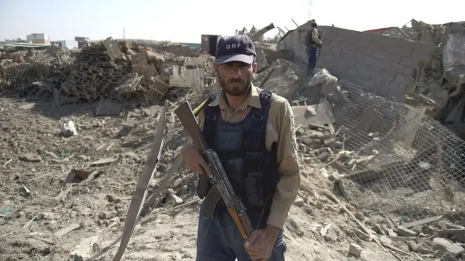 افغان سپاہی کابل میں ٹرک بم کے دھماکے سے تباہ ہونے والی عمارت کے باہر کھڑا ہے