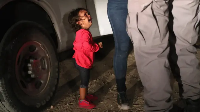 A two-year-old Honduran asylum seeker cries as her mother is searched and detained near the US-Mexico border on 12 June 2018 in McAllen, Texas.