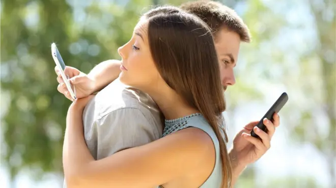 Couple texting while hugging