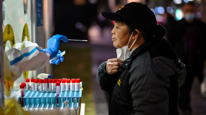 عامل صحي يأخذ عينة مسحة من امرأة لاختبار امكانية اصابتها بكوفيد-19 في شنغهاي