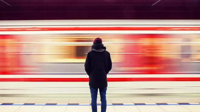 شاب ينظر إلى قطار يسير بسرعة كبيرة