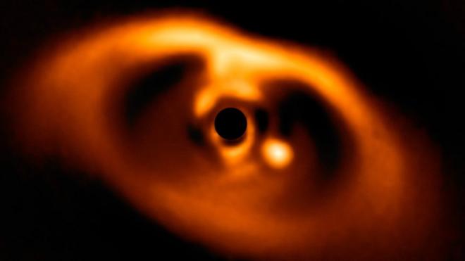 Esta es la primera imagen conocida del nacimiento de un planeta. En la imagen, el nuevo planeta corresponde al punto amarillo a la derecha del círculo oscuro en el centro de la fotografía.