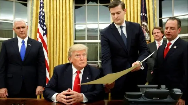 Rob Porter Donald Trump'a bir belgeyi gösterirken