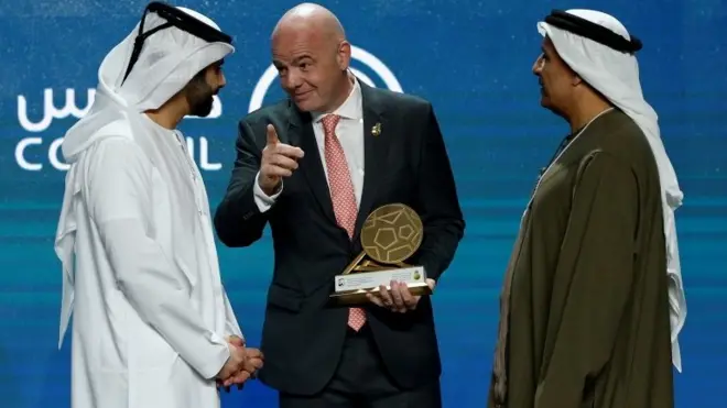 رئيس الفيفا يستلم جائزة من الشيخ منصور بن محمد بن راشد آل مكتوم (إلى اليسار)، ورئيس نادي دبي الدولي للرياضات البحرية، خلال اليوم الأول من الدورة الثالثة عشرة لمؤتمر دبي الدولي للرياضات في إمارة دبي ، الإمارات العربية المتحدة.