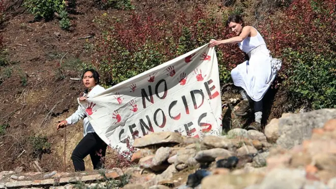 示威者手持“拒绝种族灭绝奥运会”标语闯入2022年北京冬奥圣火采集仪式现场