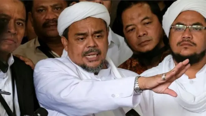 นายรีซีค (กลาง) เป็นผู้นำกลุ่มแนวร่วมผู้ปกป้องอิสลาม ซึ่งเป็นกลุ่มมุสลิมสุดโต่ง