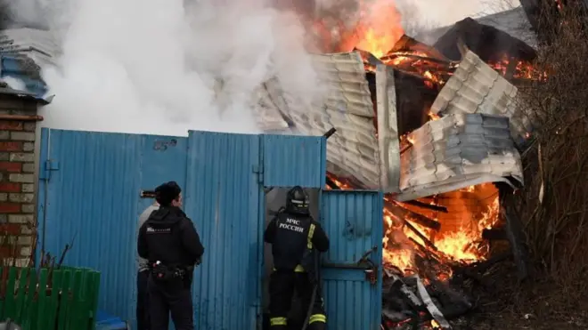 Emergency personnel tackle a blaze in the aftermath of shelling