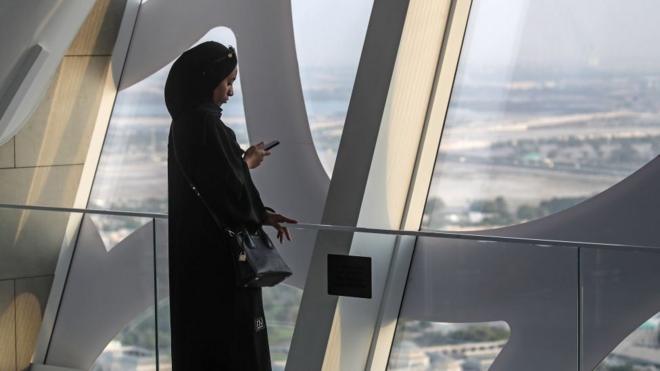 Una mujer mira su celular en la ciudad de Dubai en Emiratos Árabes Unidos