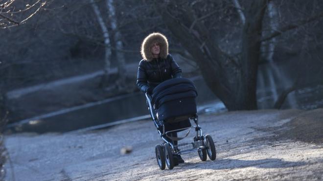 Женщина с детской коляской в парке