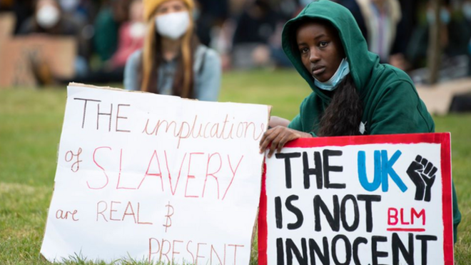 A young black girl holds placards related to the UK's slavery past in a protest in the city of Bristol