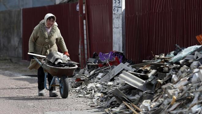 Женщина убирает завалы в Киевской области