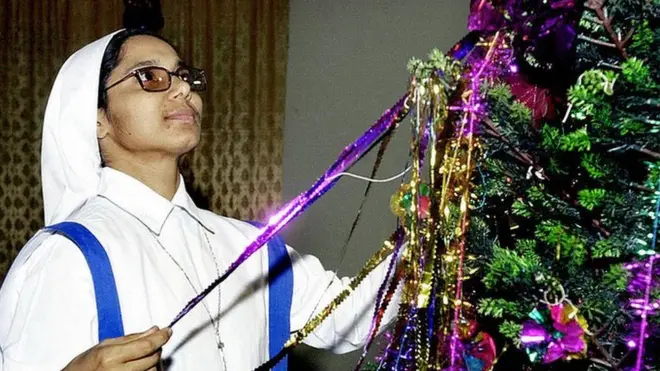 বড়দিনের ক্রিসমাস ট্রি সাজাচ্ছেন একজন ধর্মযাজিকা
