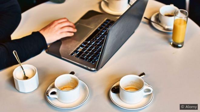 Pessoa usando laptop com várias xícaras de café em volta