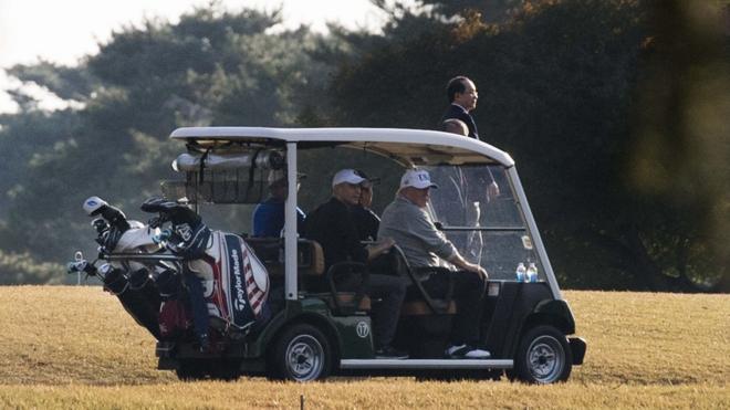 Donald Trump (front R) and Japanese Prime Minister Shinzo Abe (front L) return in a golf cart after playing a round of golf