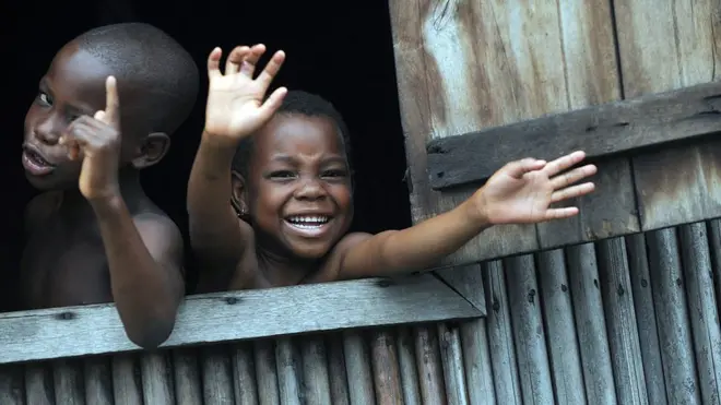 Des enfants font signe de la main par une fenêtre ouverte dans le bidonville de Makoko à Lagos