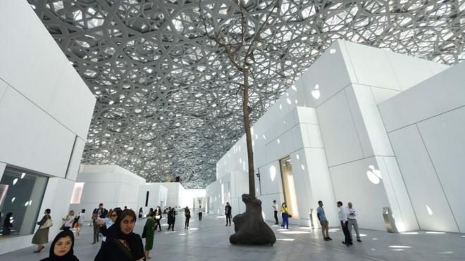 People walk near a sculpture by Italian artist Giuseppe Penone at the Louvre Abu Dhabi Museum on 7 November 2017, on the eve of the official opening of the museum on Saadiyat island in the Emirati capital.