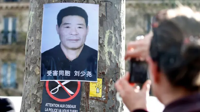 巴黎共和国广场悼念刘少尧集会现场一名男子朝着贴在树上的刘少尧遗照拍照（2/4/2017）