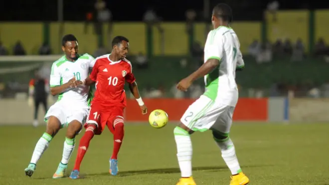 لاعب المنتخب السوداني، مهند الطاهر، أمام لاعبيين من المنتخب النيجيري في تصفيات كأس أمم أفريقيا