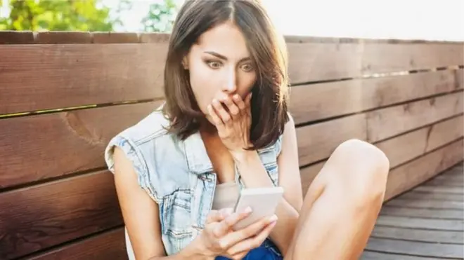 Жінка дивитися в телефон у шоці