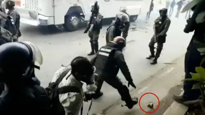 Un guardia nacional recoje una bomba lacrimógena
