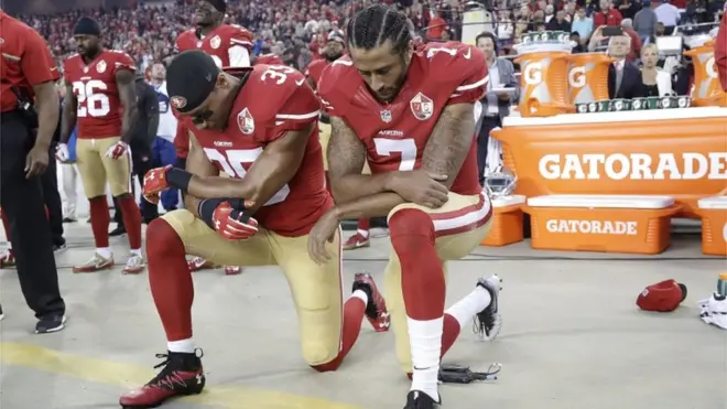 Eric Reid et Colin Kaepernick mettant un genou au sol durant l'hymne national américain