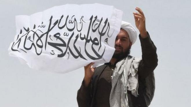 Un hombre afgano ondea la bandera del Talibán en la frontera con Pakistán, 17 de julio, 2021