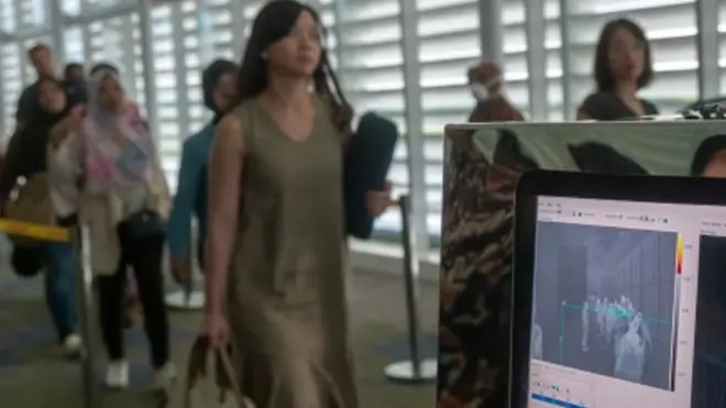 Petugas Kantor Kesehatan Pelabuhan (KKP) Semarang memindai penumpang pesawat asal Singapura menggunakan alat deteksi suhu tubuh di Bandara Internasional Jenderal Ahmad Yani, Semarang, Jumat (24/01).