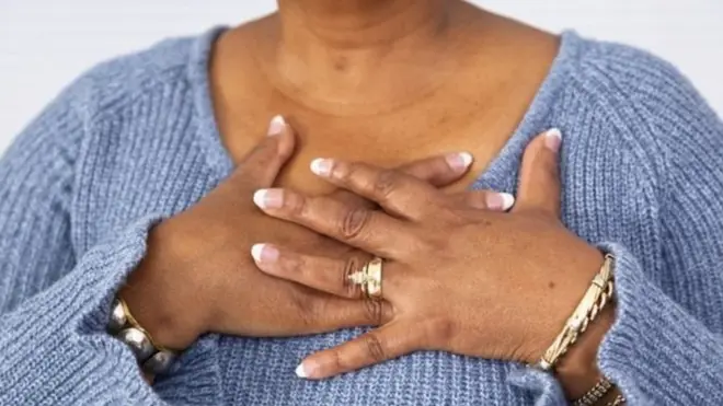 Woman wey im hold hand for chest