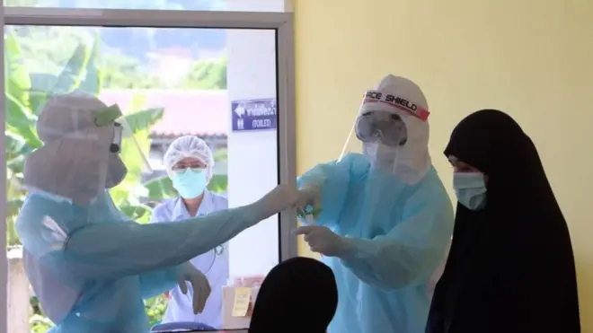 เจ้าหน้าที่สาธารณสุขเตรียบเก็บตัวอย่างจากหญิงมุสลิมที่หมู่บ้านแห่งหนึ่งใน จ.ยะลา เพื่อตรวจหาเชื้อไวรัสโคโรนาสายพันธุ์ใหม่