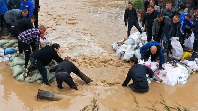 Aerial view of people working to block a dyke breach at a section of Fenhe River in Jishan County