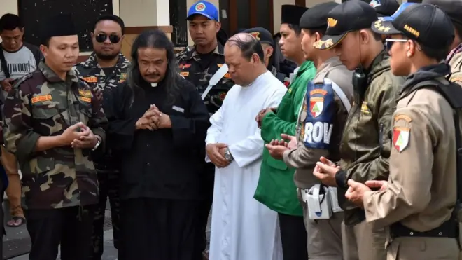 Ketua GP Ansor Jateng, Sholahudin Aly (kiri), rohaniawan Katolik Romo Aloys Budi Purnomo (kedua kiri), rohaniawan Romo Notowardoyo (ketiga kiri), bersama sejumlah anggota Banser berdoa bersama untuk korban peristiwa bom Surabaya, Minggu (13/5).